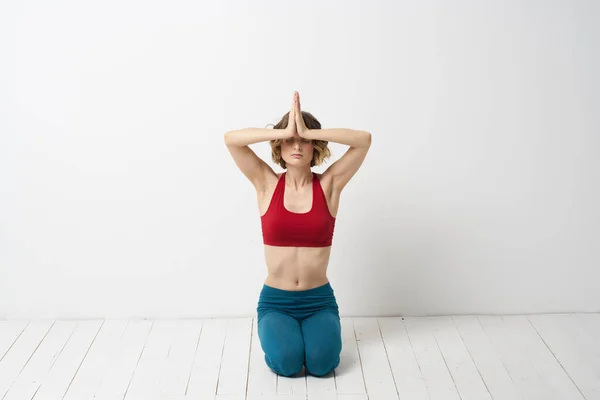 一位穿蓝色牛仔裤的妇女在室内浅色的背景下练习瑜伽，一位体形纤细的体操运动员在室内练习瑜伽 — 图库照片