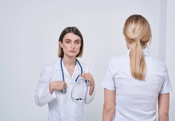 Профессиональная медсестра пожимает руку пациентке и стетоскоп вокруг шеи — стоковое фото