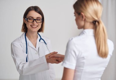 Doktor ve hasta, arka planda hafif bir steteskop üzerinde el sıkışıyor.