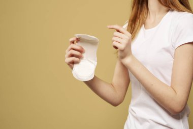 Elinde bej bir arka planda temiz bir ped olan kız regl döneminin kritik günlerini gördü.