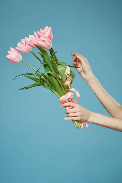 Un ramo de flores en las manos de un regalo de vacaciones romance fondo azul — Foto de Stock