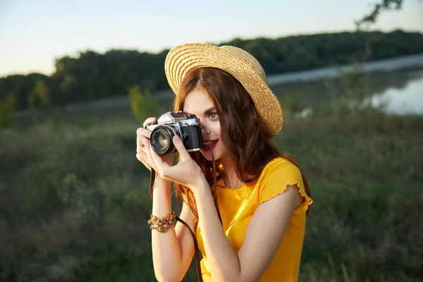 Fotografer wanita melihat ke dalam lensa kamera mengenakan topi di luar ruangan mengambil gambar — Stok Foto