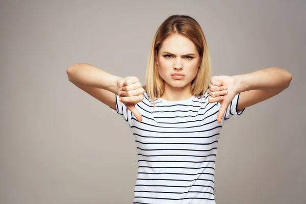 Una donna con un'espressione dispiaciuta sta gesticolando con le mani T-shirt sfondo grigio — Foto Stock