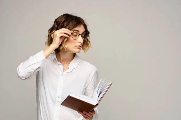 Femme d'affaires avec bloc-notes et lunettes sur un fond clair coiffure succès émotions — Photo