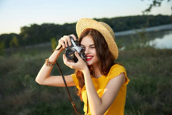 Жінка-фотограф в капелюсі, дивлячись в об'єктив камери посміхається природі хобі — стокове фото