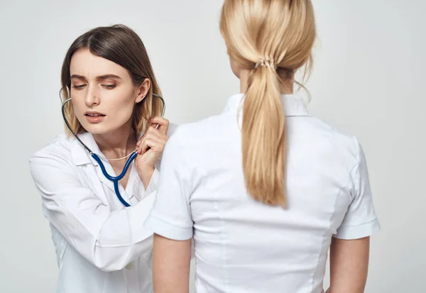 Infermiere in stetoscopio camice medico e vista posteriore del paziente — Foto Stock