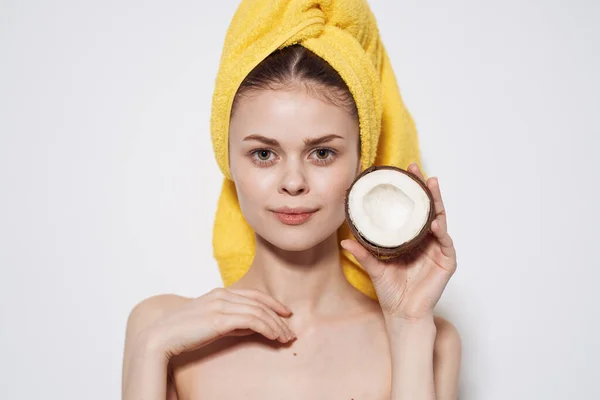 Vacker kvinna med gul handduk på huvudet håller händer kokos exotisk ren hud spa — Stockfoto