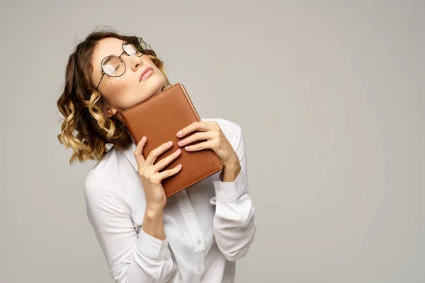 Femme d'affaires avec bloc-notes et lunettes sur un fond clair coiffure succès émotions — Photo