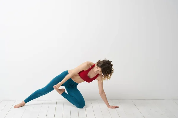 stock image A woman in blue jeans practices yoga on a light background indoors and a slim figure in gymnastics