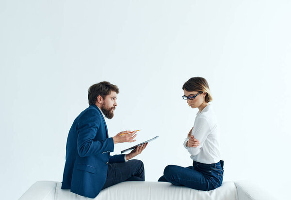 Woman and man are sitting on the couch in suits psychology papers