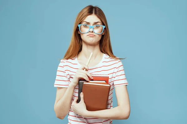 Meisje in modieuze bril met notebooks in handen op een blauwe achtergrond bijgesneden uitzicht Copy Space — Stockfoto