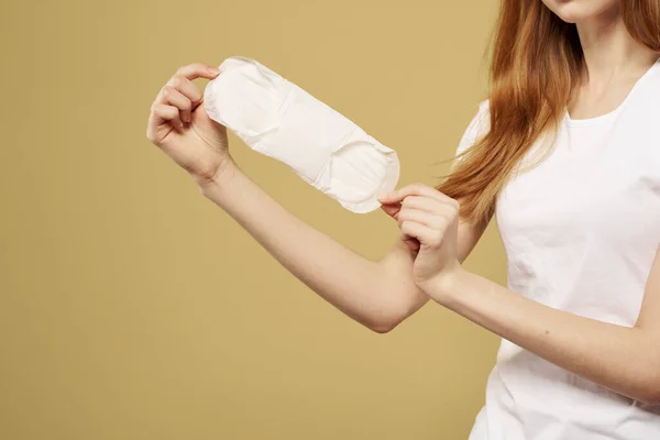 Girl with a clean pad in her hand on a beige background cropped view of menstruation critical days hygiene — Stock Photo, Image