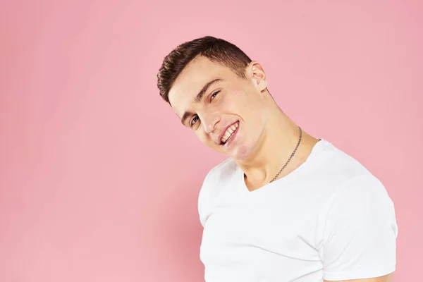 Glada stilig man i vit t-shirt känslor rosa isolerad bakgrund — Stockfoto