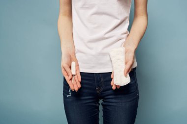 Elinde tampon ve yastıkla mavi arka plan hijyen temizliği regl olmuş bir kız.