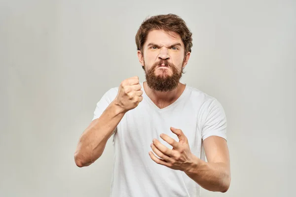 Бородатий чоловік жестикулює руками на світлому фоні білої футболки агресії — стокове фото