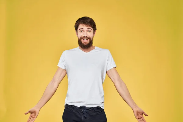 Man gesturing με τα χέρια συναισθήματα lifestyle λευκό t-shirt κίτρινο απομονωμένο φόντο — Φωτογραφία Αρχείου