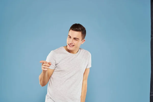 Glad man i en vit t-shirt gester med händerna känslor blå bakgrund — Stockfoto