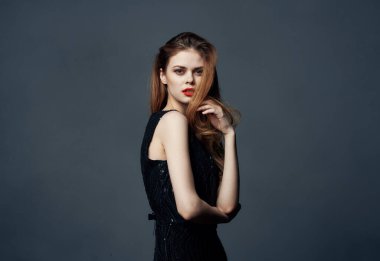 Siyah elbiseli kızıl saçlı kadın elleriyle işaret ediyor. Makyaj modeline sarılıyor.