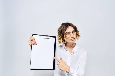Elinde beyaz dökümanların olduğu bir klasör olan iş kadını arka planda ve saç stili gözlüklü model