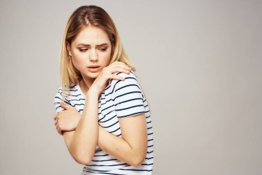 Çizgili tişörtlü bir kadın ellerini duygularının önünde tutar hoşnutsuz arka plan