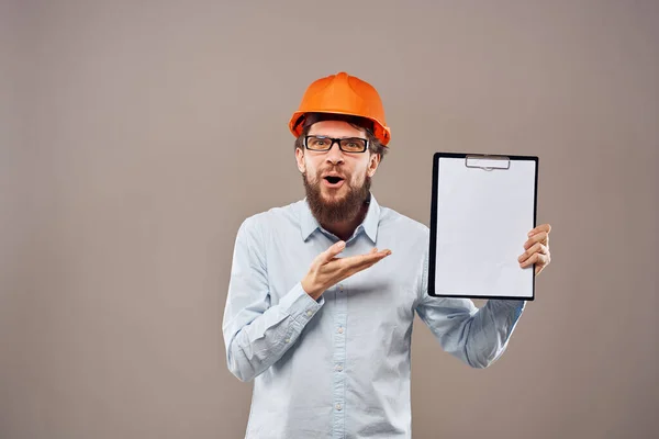 Um homem de camisa com um chapéu laranja duro engenheiro documentos de trabalho prestação de serviços — Fotografia de Stock