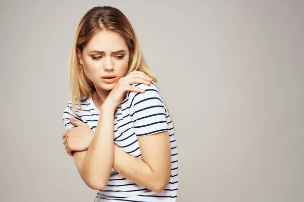 Una donna in una maglietta a righe tiene le mani davanti alle sue emozioni dispiaciuto sfondo leggero — Foto Stock