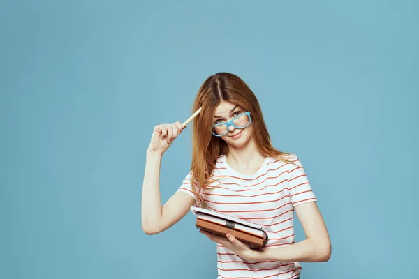 Chica en gafas de moda con cuadernos en las manos sobre un fondo azul recortado vista Copiar espacio —  Fotos de Stock