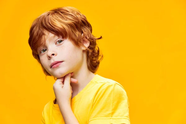 Söt rödhårig pojke håller hand på haka t-shirt studio — Stockfoto