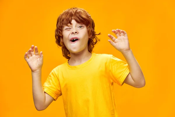 Junge mit rotem Haar zwinkert und öffnet den Mund weit auf gelbem Hintergrund. — Stockfoto