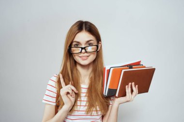 Sırtında not defteri ve sırt çantası olan bayan öğrenci bilim gözlüklerini kırpmış.