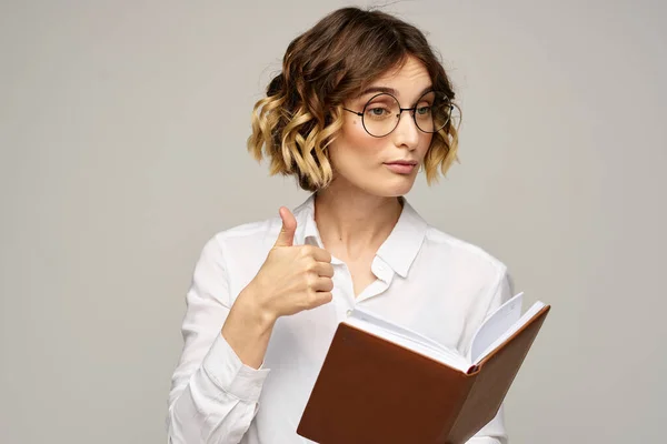 Femme avec bloc-notes dans les mains travail d'affaires beige fond lunettes coiffure — Photo