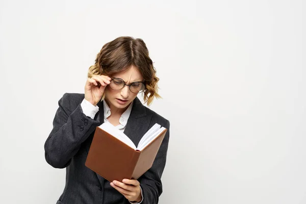 Woman at work with book in hand light background classic suit glasses head — Stock Photo, Image