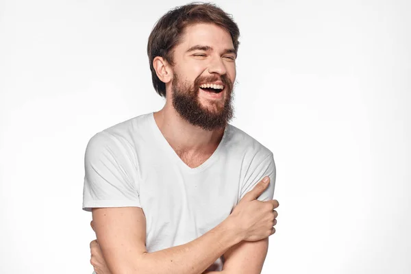Vrolijk baard man in een wit t-shirt emoties gebaren met zijn handen licht achtergrond studio — Stockfoto