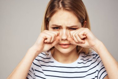 Çizgili tişörtlü bir kadın ellerini duygularının önünde tutar hoşnutsuz arka plan