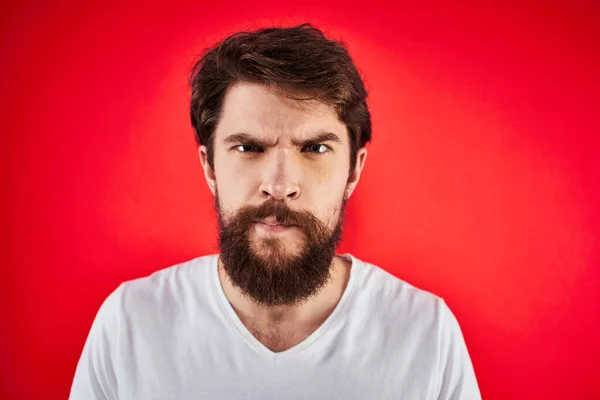 Uomo in t-shirt gesticolare con le mani insoddisfazione studio rosso uniforme — Foto Stock