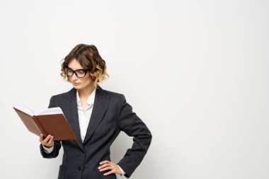 Klasik takım elbiseli bir iş kadını elinde bir not defteri ve yüzünde gözlüklerle.