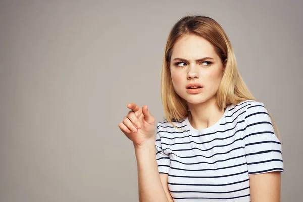 Uma mulher com uma expressão descontente está gesticulando com as mãos T-shirt fundo cinza — Fotografia de Stock