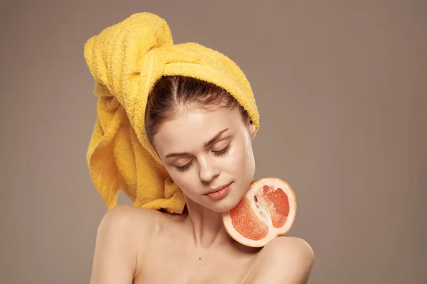 Woman with bare shoulders yellow towel on her head grapefruit in hands clean skin care — Stock Photo, Image