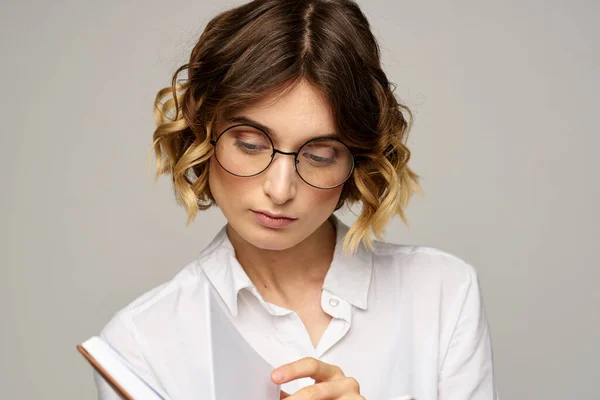 Femme d'affaires avec bloc-notes et lunettes sur un fond clair coiffure succès émotions — Photo