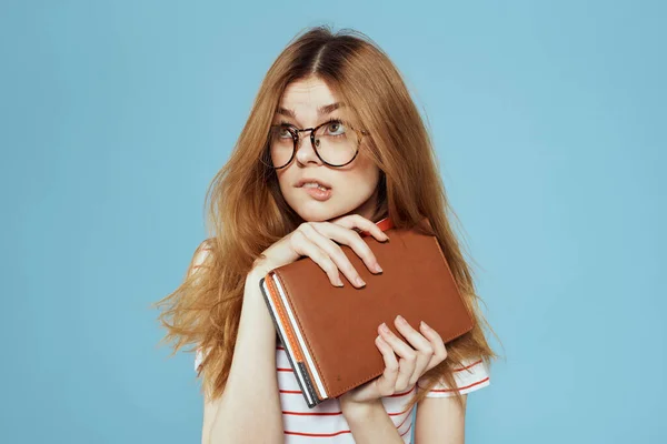 Estudante feminino enérgico com blocos de notas e óculos modelo fundo azul — Fotografia de Stock