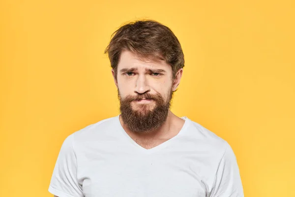 Bearded man i en vit T-shirt gester med händerna känslor studio gul bakgrund — Stockfoto