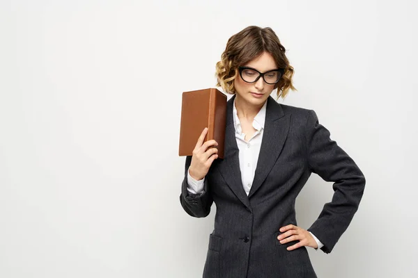 Klasik takım elbiseli bir iş kadını elinde bir not defteri ve yüzünde gözlüklerle. — Stok fotoğraf
