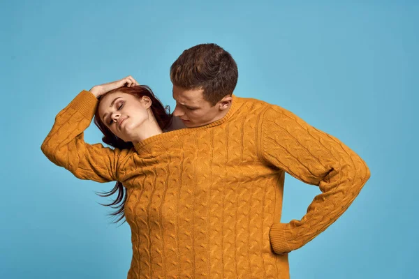 Paar in gelbem Pullover posiert vor blauem Hintergrund — Stockfoto