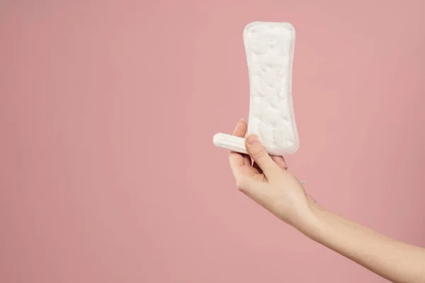 Podkładka ochronna i tampon w rękach kobiet na różowym tle menstruacja krytyczne dni — Zdjęcie stockowe