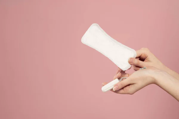 Almofada protetora e tampão em mãos femininas em um fundo rosa menstruação dias críticos — Fotografia de Stock