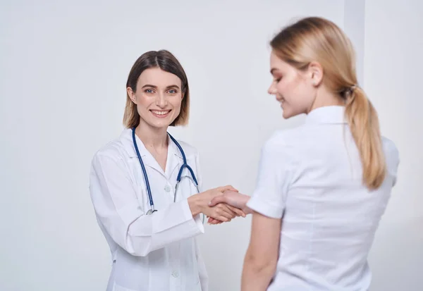 Medico infermiere professionista stringe la mano a un paziente e uno stetoscopio intorno al collo — Foto Stock