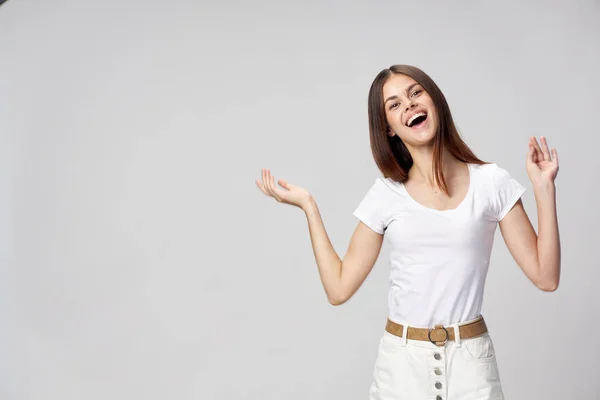 Felice gesti donna con le mani in una t-shirt bianca e in pantaloncini bottoni cintura beige — Foto Stock