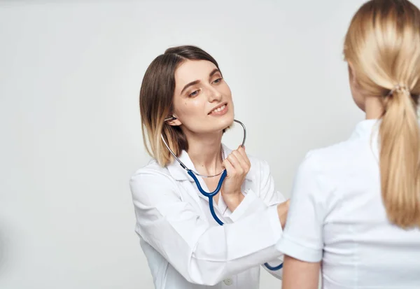 白いTシャツを着た患者に何かを説明する看護師の医者 — ストック写真