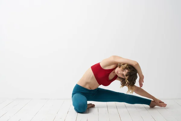La chica se dedica al yoga sobre un fondo claro Camiseta roja gesticulando con sus manos —  Fotos de Stock