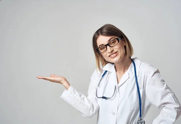 Donna infermiera in un abito medico gesticolando con le mani su uno spazio luce copia di sfondo — Foto Stock